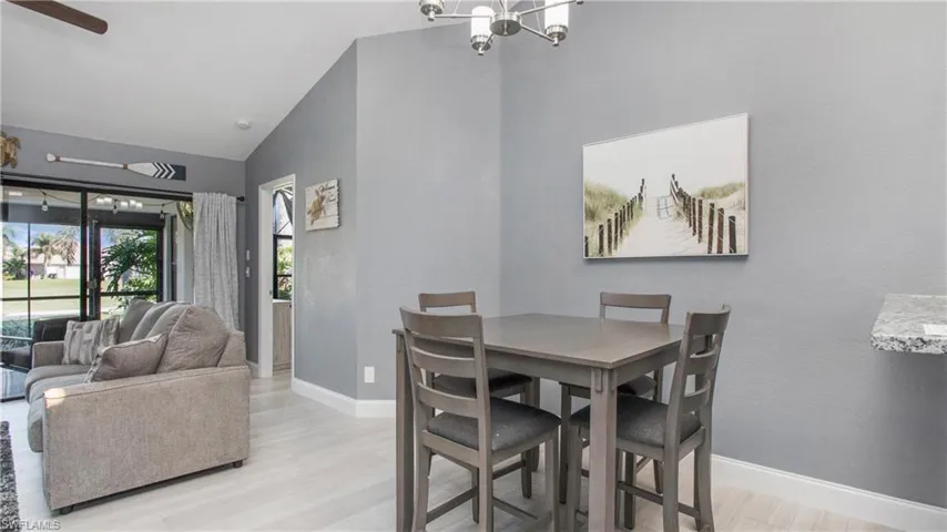 Dining area with ceiling fan with notable chandelier, vaulted ceiling, and light wood-type flooring