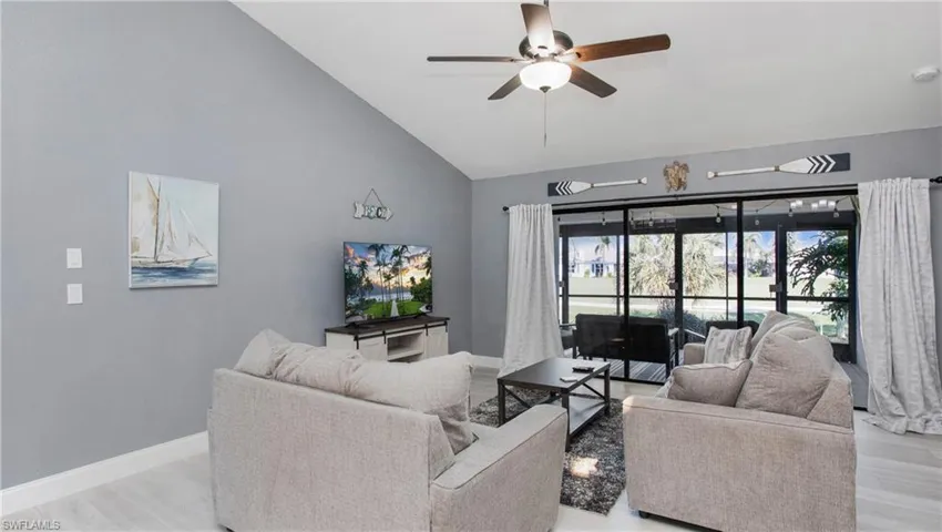 Living room with light hardwood / wood-style flooring, ceiling fan, and lofted ceiling