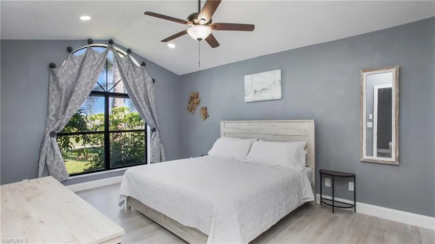 Bedroom with ceiling fan, vaulted ceiling, light wood-type flooring, and multiple windows