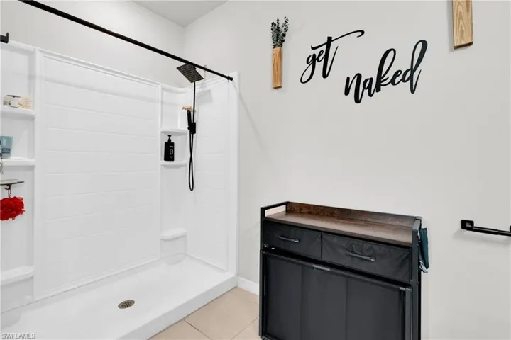 Full bath featuring light tile patterned floors, a shower stall, and vanity