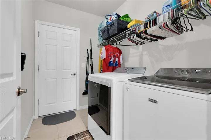 Laundry area with washing machine and clothes dryer and light tile patterned floors