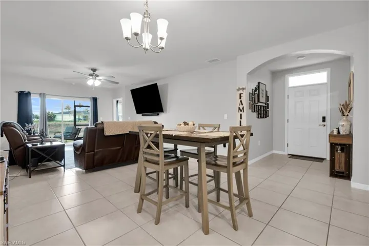 Dining room featuring arched walkways, light tile patterned floors, hanging lights, and ceiling fan