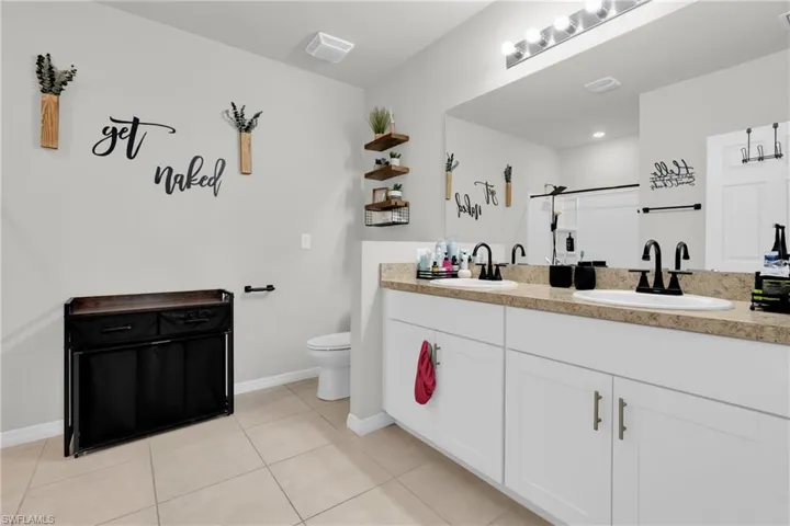 Full bath with double vanity and light tile patterned floors