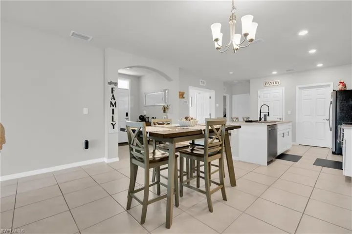 Dining area with arched walkways, light tile patterned flooring, and a chandelier