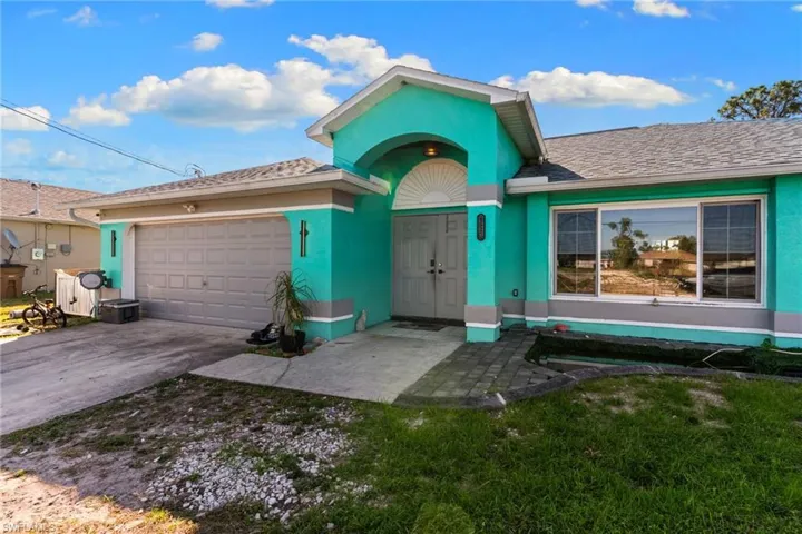 View of front of house with an attached garage, driveway, a front yard, and stucco siding