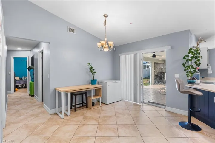 Dining area with vaulted ceiling, a chandelier, light tile patterned floors, and a ceiling fan