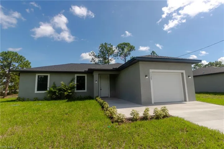 Single story home featuring stucco siding, a garage, driveway, and a front lawn