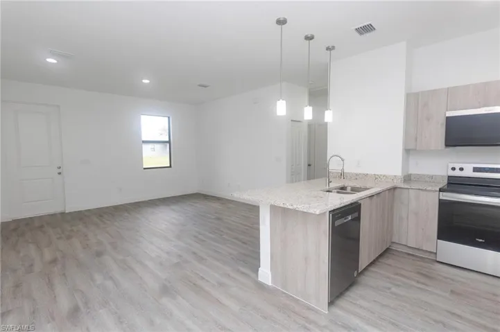 Kitchen featuring electric range, light brown cabinetry, modern cabinets, and dishwashing machine
