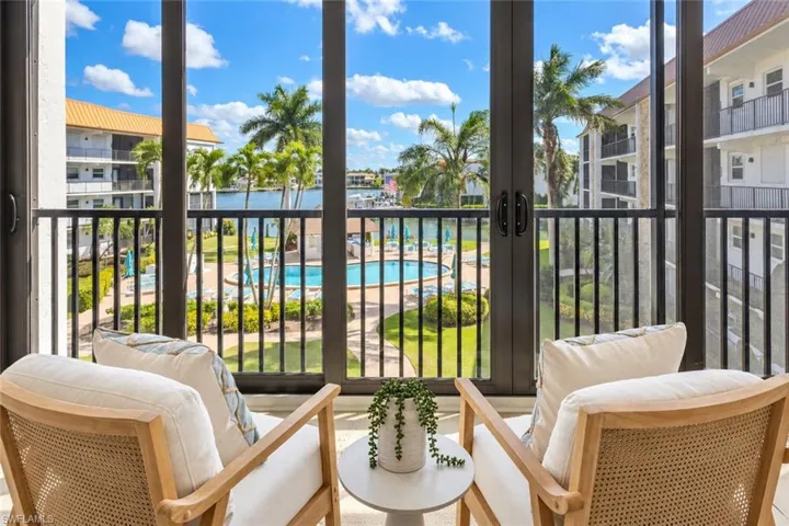 Waterfront community grounds featuring a swimming pool, paved walkways, mature palm trees, and a shaded gazebo