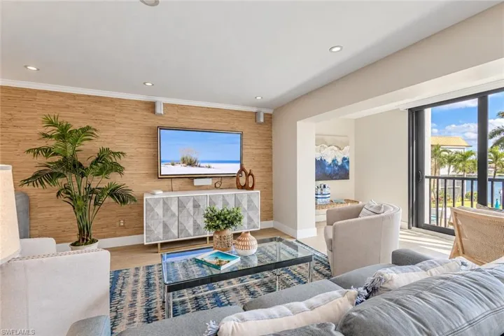 Living area featuring a textured wood-finished accent wall, recessed lighting, and sliding glass doors with exterior access
