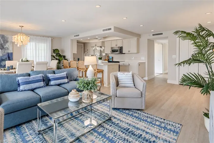 Open-concept living space featuring wood-finish flooring, recessed lighting, cabinetry with neutral-tone finishes, stainless steel appliances, and an integrated kitchen island