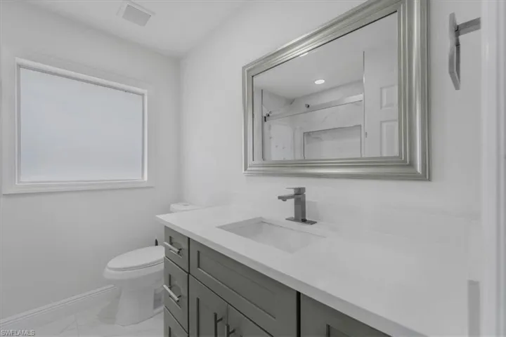 Full bathroom with vanity, a marble finish shower, and light marble finish flooring