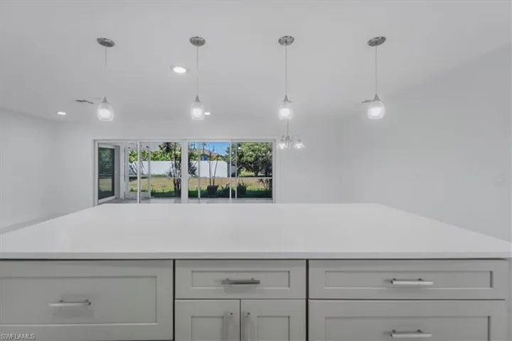 Kitchen with light stone counters, a center island, and pendant lighting