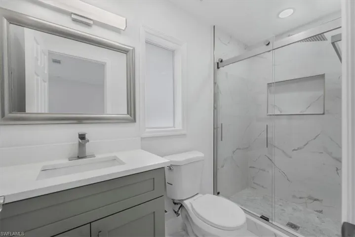 Full bath featuring vanity and a marble finish shower