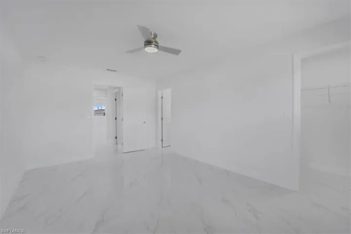 Unfurnished room with ceiling fan and light marble finish floors