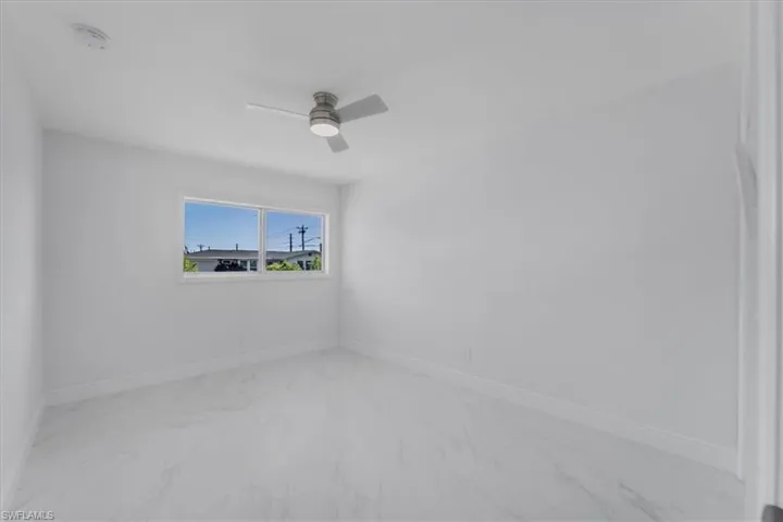 Unfurnished room featuring light marble finish floors, a ceiling fan, and a smoke detector