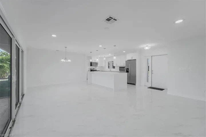 Unfurnished living room featuring light marble finish floors and hanging lights