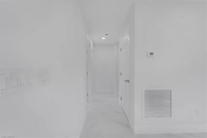 Hall featuring baseboards and light marble finish flooring