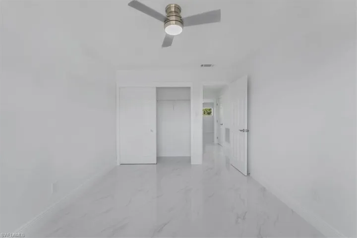 Unfurnished bedroom with a closet, light marble finish floors, and ceiling fan