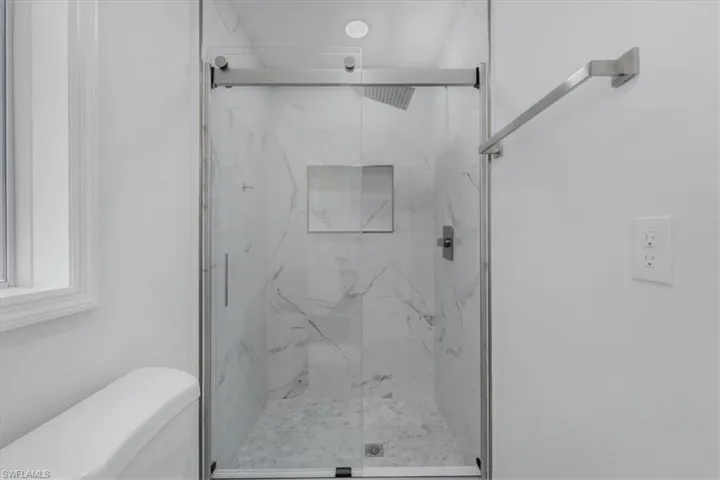 Bathroom featuring a marble finish shower and toilet