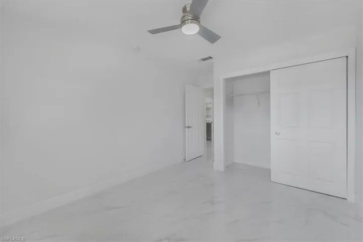 Unfurnished bedroom featuring light marble finish flooring, a closet, and ceiling fan