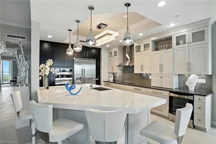 Kitchen with decorative light fixtures, light tile patterned flooring, decorative backsplash, wine cooler, and appliances with stainless steel finishes - Virtually Edited Image