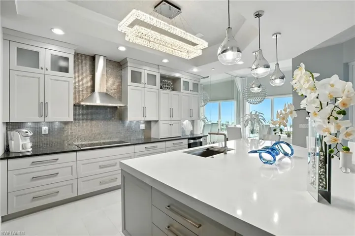 Kitchen with wall chimney range hood, glass insert cabinets, gray cabinetry, pendant lighting, and recessed lighting - Virtually Edited Image