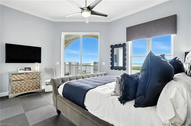 Bedroom with a ceiling fan, crown molding, access to exterior, and dark carpet - Virtually Edited Image
