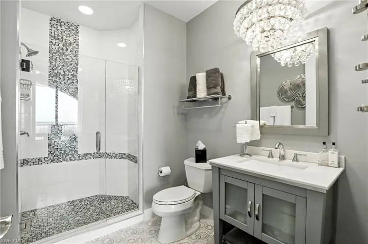 Full bath featuring a stall shower, vanity, a chandelier, light tile patterned floors, and recessed lighting - Virtually Edited Image