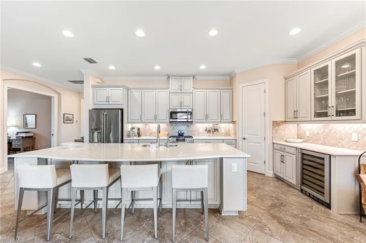 Kitchen featuring wine cooler, visible vents, a sink, a kitchen island with sink, and appliances with stainless steel finishes