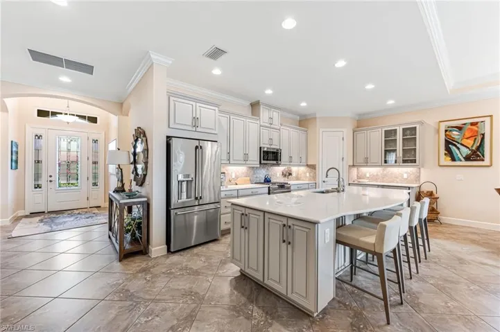 Kitchen featuring a sink, visible vents, high end appliances, crown molding, and a breakfast bar area