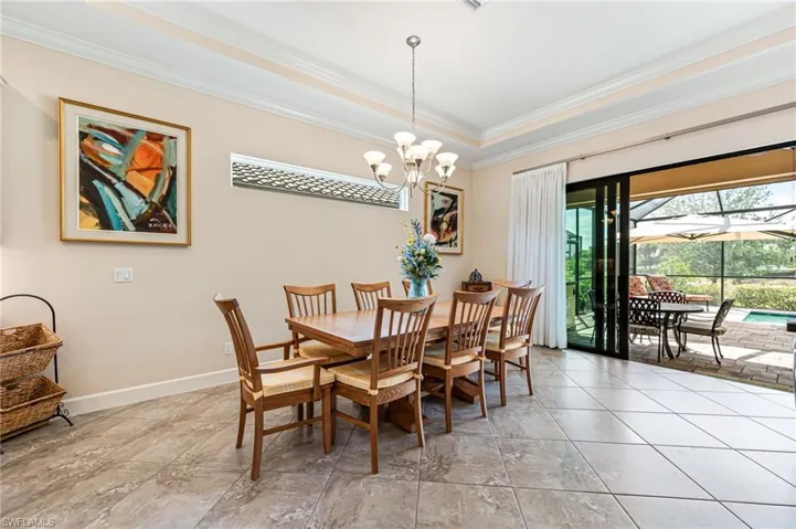 Dining area featuring baseboards, a tray ceiling, a chandelier, and crown molding