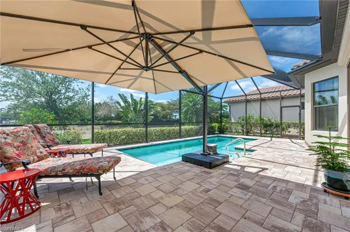 Outdoor pool featuring glass enclosure and a patio