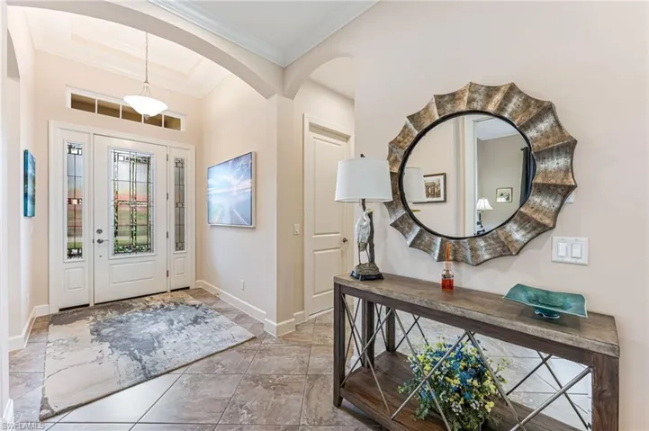 Entrance foyer featuring baseboards, arched walkways, and crown molding