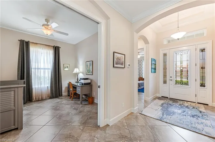 Entrance foyer featuring ceiling fan, baseboards, arched walkways, and ornamental molding