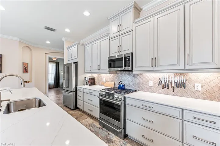 Kitchen with stainless steel appliances, a sink, tasteful backsplash, visible vents, and crown molding