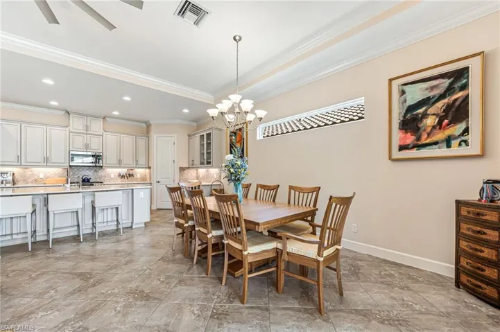Dining area with baseboards, visible vents, an inviting chandelier, recessed lighting, and ornamental molding