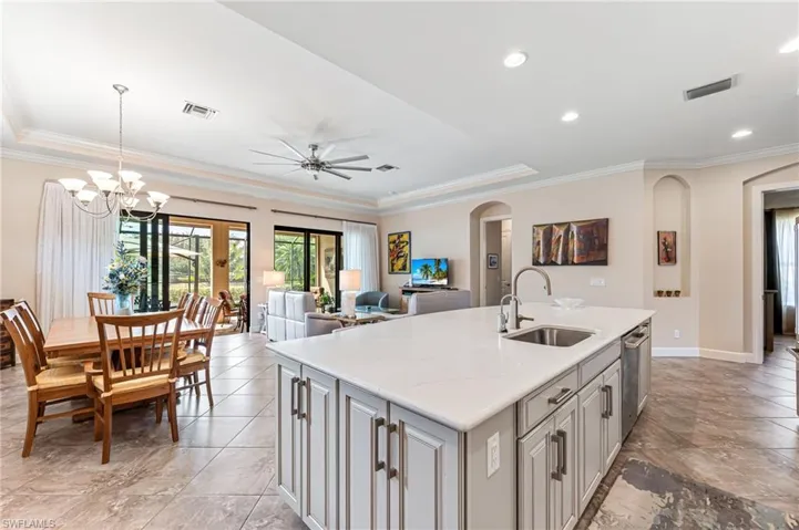 Kitchen featuring arched walkways, a tray ceiling, a sink, and visible vents