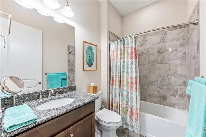 Bathroom featuring shower / bath combo with shower curtain, vanity, tile patterned flooring, and toilet