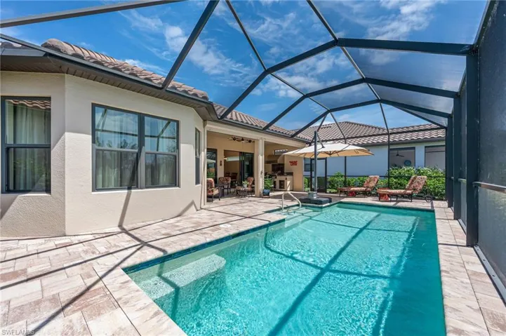 Pool featuring glass enclosure, a patio area, and a ceiling fan