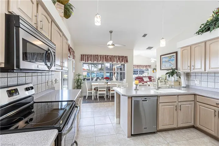 Oversized kitchen with all newer stainless appliances, wood cabinetry and lovely corian countertops has lots of counter space as it leads you to the large family room,