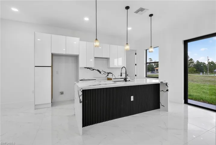 Modern kitchen featuring a waterfall island with black fluted detailing and a black faucet