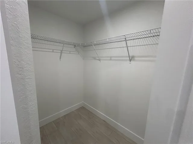 Walk in closet with light wood finished floors