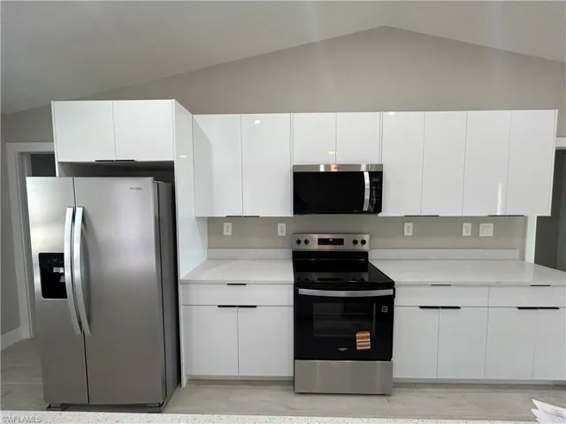 Kitchen featuring stainless steel appliances, white cabinetry, modern cabinets, and light stone counters