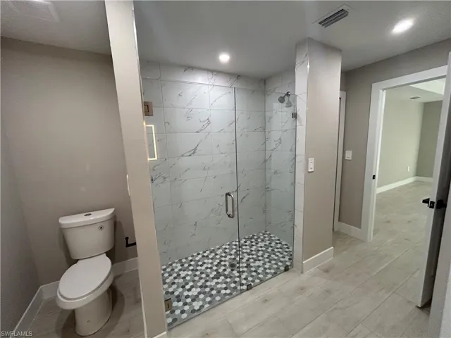 Full bathroom featuring a marble finish shower and recessed lighting