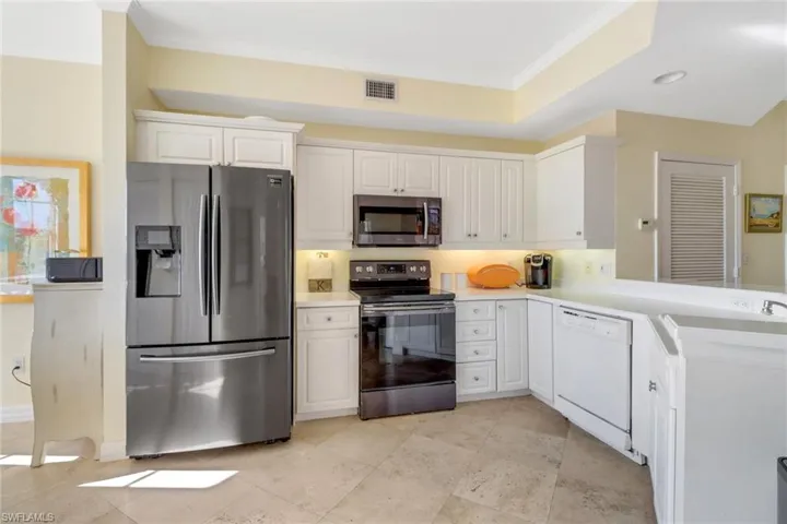 Kitchen featuring appliances with stainless steel finishes, ornamental molding, sink, and white cabinets