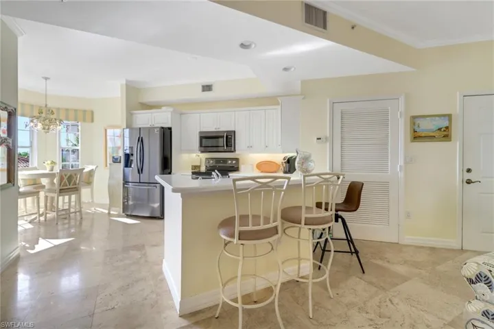 Kitchen with white cabinetry, a kitchen bar, an inviting chandelier, stainless steel appliances, and decorative light fixtures