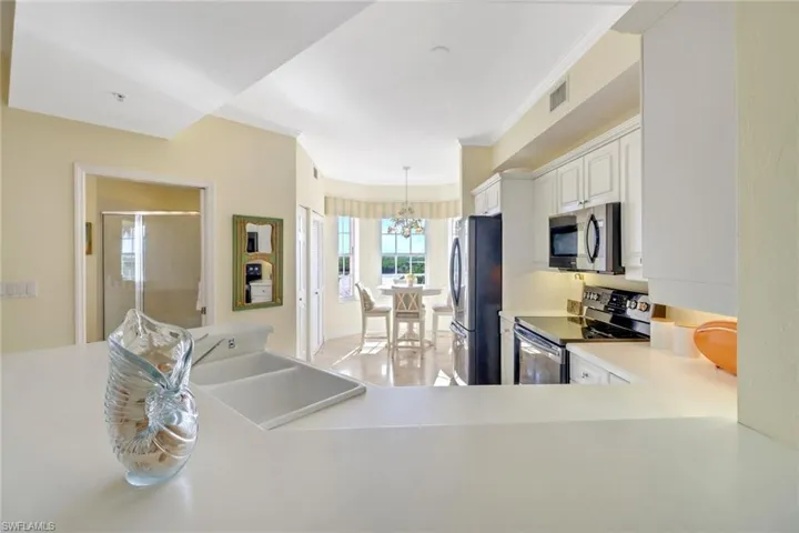 Kitchen featuring appliances with stainless steel finishes, white cabinets, an inviting chandelier, decorative light fixtures, and sink