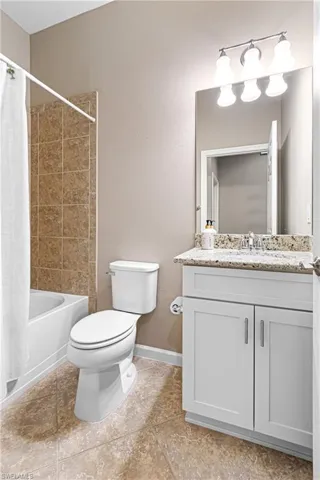 Bathroom with vanity, shower / bathtub combination with curtain, and tile patterned floors