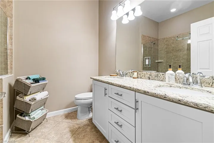 Bathroom featuring double vanity, a tile shower, and tile patterned floors